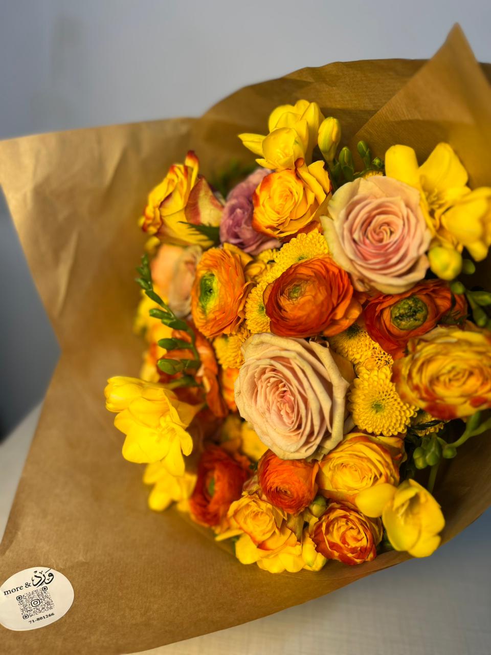 Yellow and orange ranunculus with freesia in brown kraft wrapper
